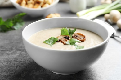 Photo of Bowl of fresh homemade mushroom soup on gray table