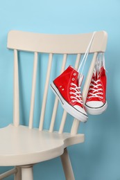 Photo of Pair of sneakers hanging on chair near light blue wall