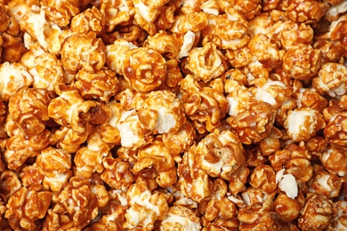 Photo of Sweet tasty caramel popcorn as background, top view