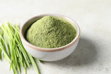 Photo of Wheat grass powder in bowl and fresh sprouts on light table, closeup