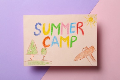 Photo of Card with text SUMMER CAMP and drawings on color background, top view
