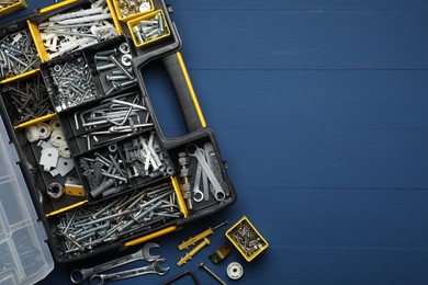 Organizer with many different fasteners and wrenches on blue wooden table, flat lay. Space for text