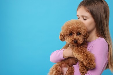 Photo of Little child with cute puppy on light blue background, space for text. Lovely pet