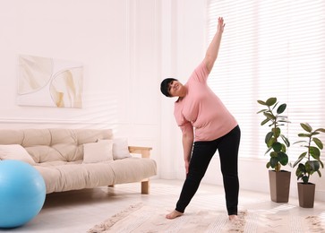 Photo of Overweight mature woman stretching at home, space for text