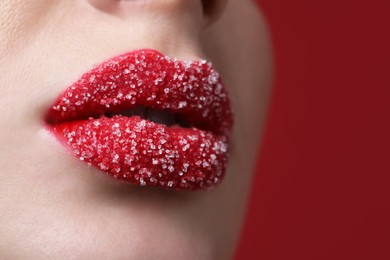 Photo of Young woman with beautiful lips covered in sugar on red background, closeup