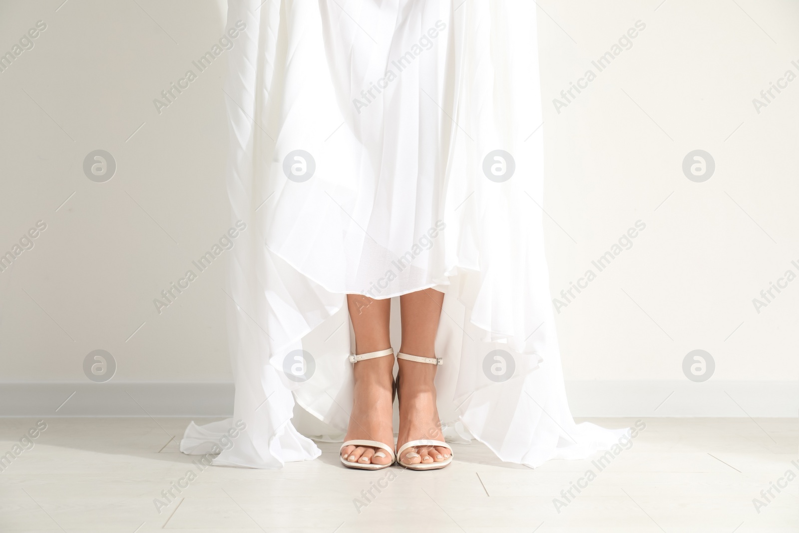 Photo of Young bride wearing beautiful wedding dress near light wall, closeup