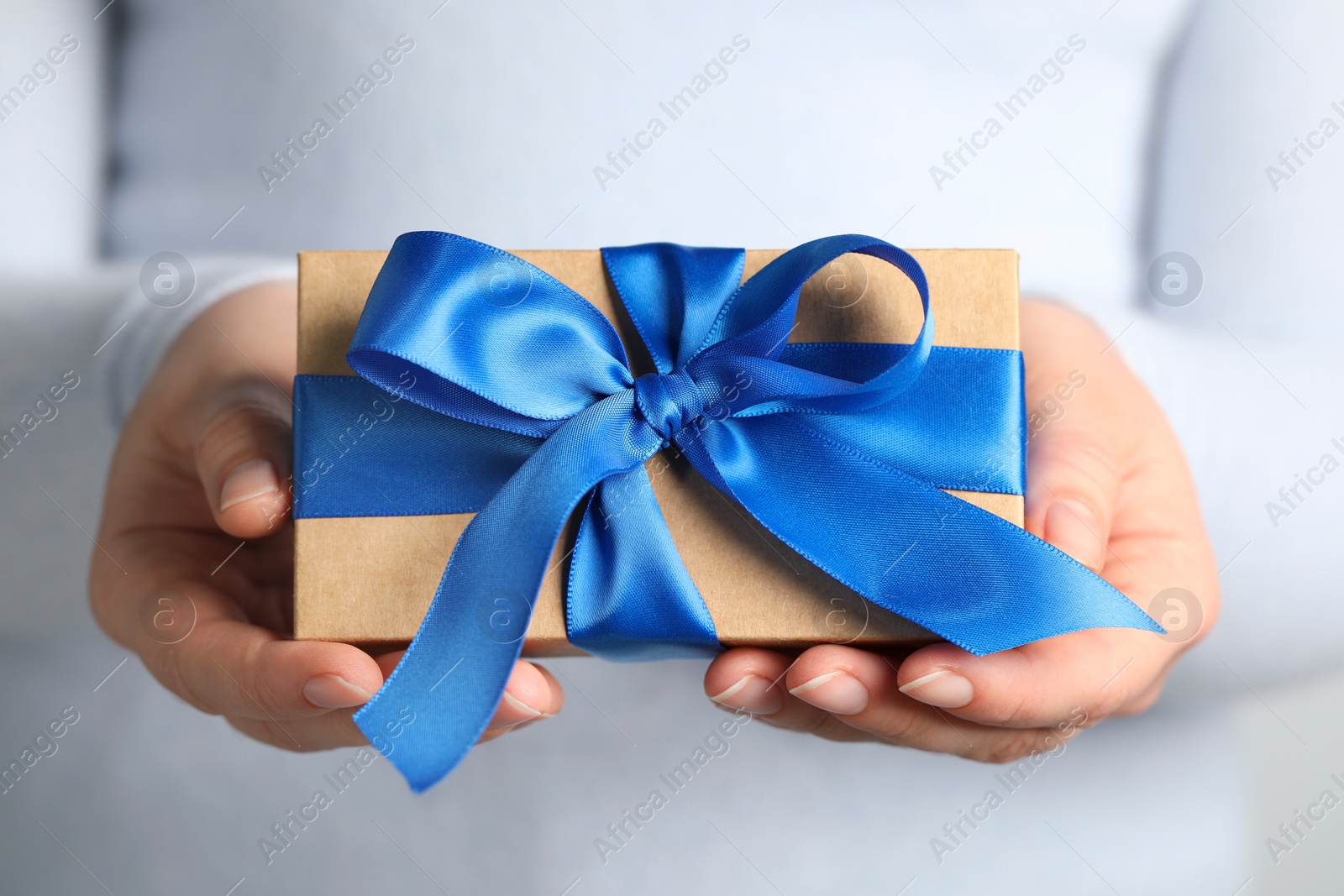 Photo of Woman holding gift box with blue bow, closeup