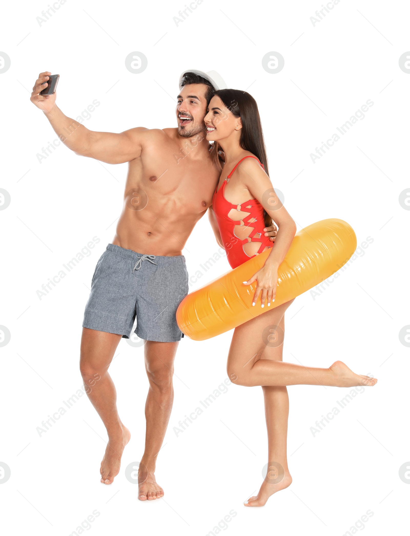 Photo of Young attractive couple in beachwear with inflatable ring taking selfie on white background