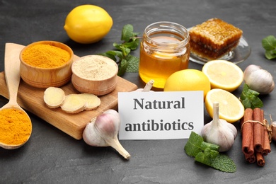 Photo of Different fresh products and card with phrase Natural Antibiotic on black table