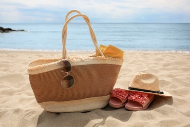 Photo of Stylish bag and other beach items on sandy seashore