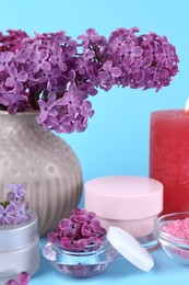 Photo of Cosmetic products and lilac flowers on light blue background
