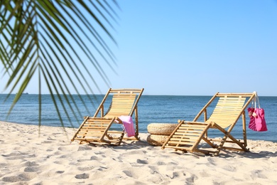 Wooden sunbeds and beach accessories on sandy shore