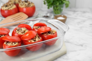 Photo of Delicious stuffed tomatoes with minced beef, bulgur and mushrooms in glass baking dish on white table. Space for text