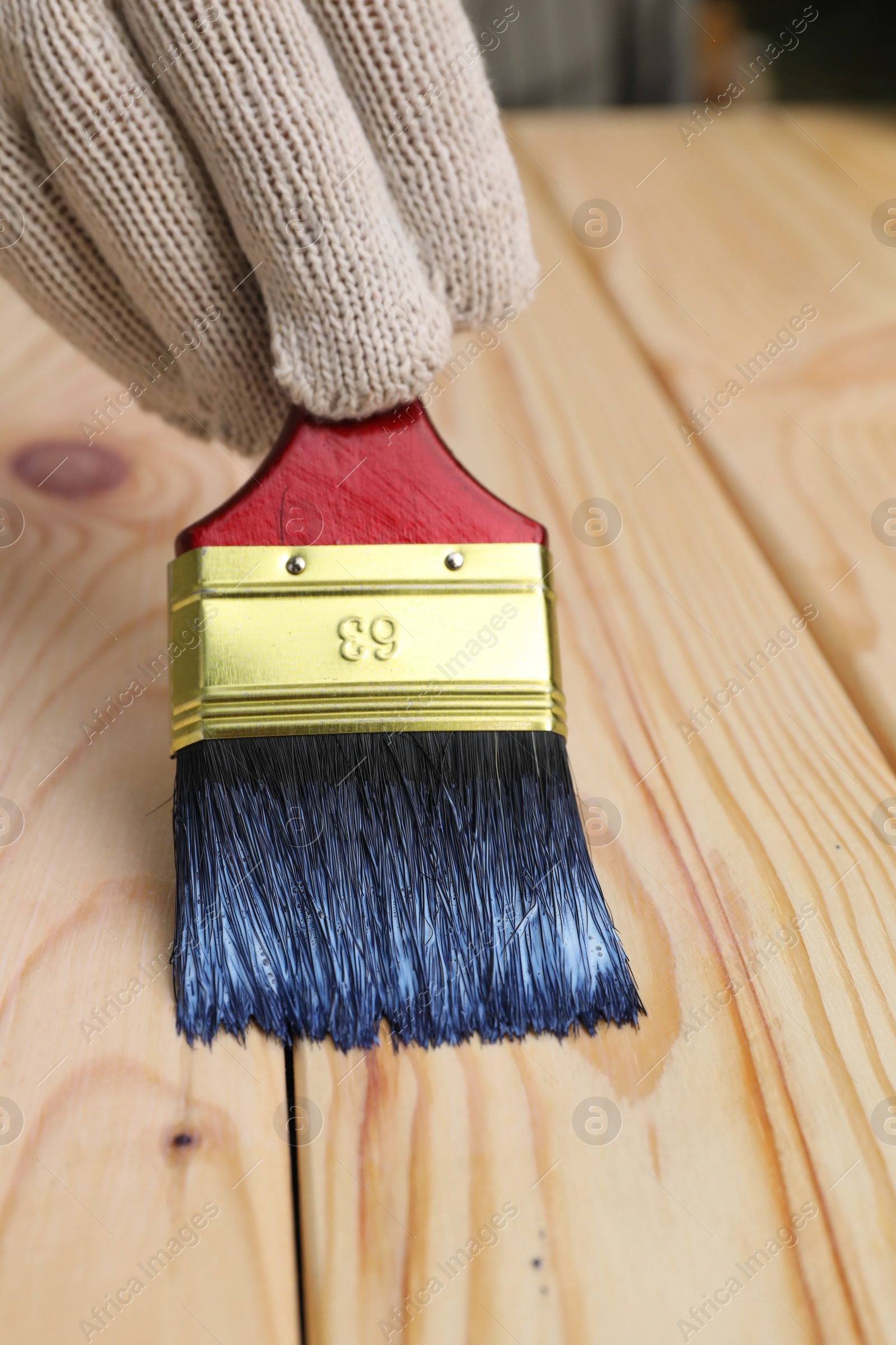 Photo of Man varnishing wooden surface with brush, closeup