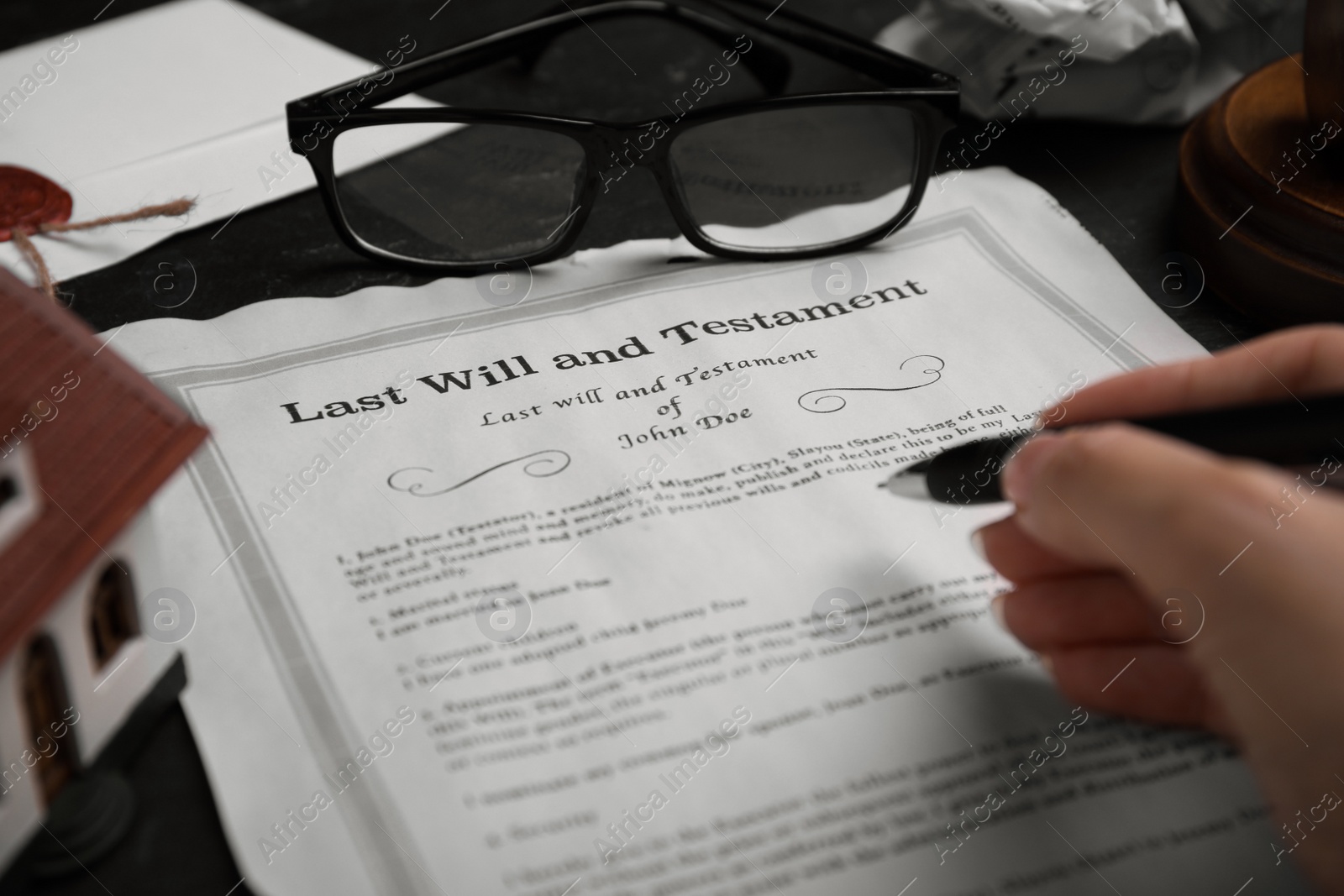 Photo of Woman signing last will and testament at black table, closeup