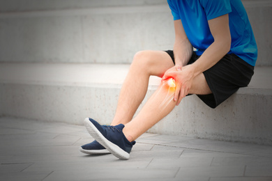 Man suffering from knee pain on stairs, closeup