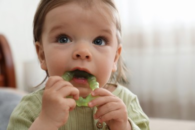 Cute baby girl with teething toy at home, closeup