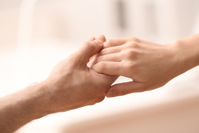 People holding hands against blurred background, closeup