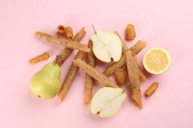 Photo of Delicious fruit leather rolls, pears and lemon on pink background, flat lay