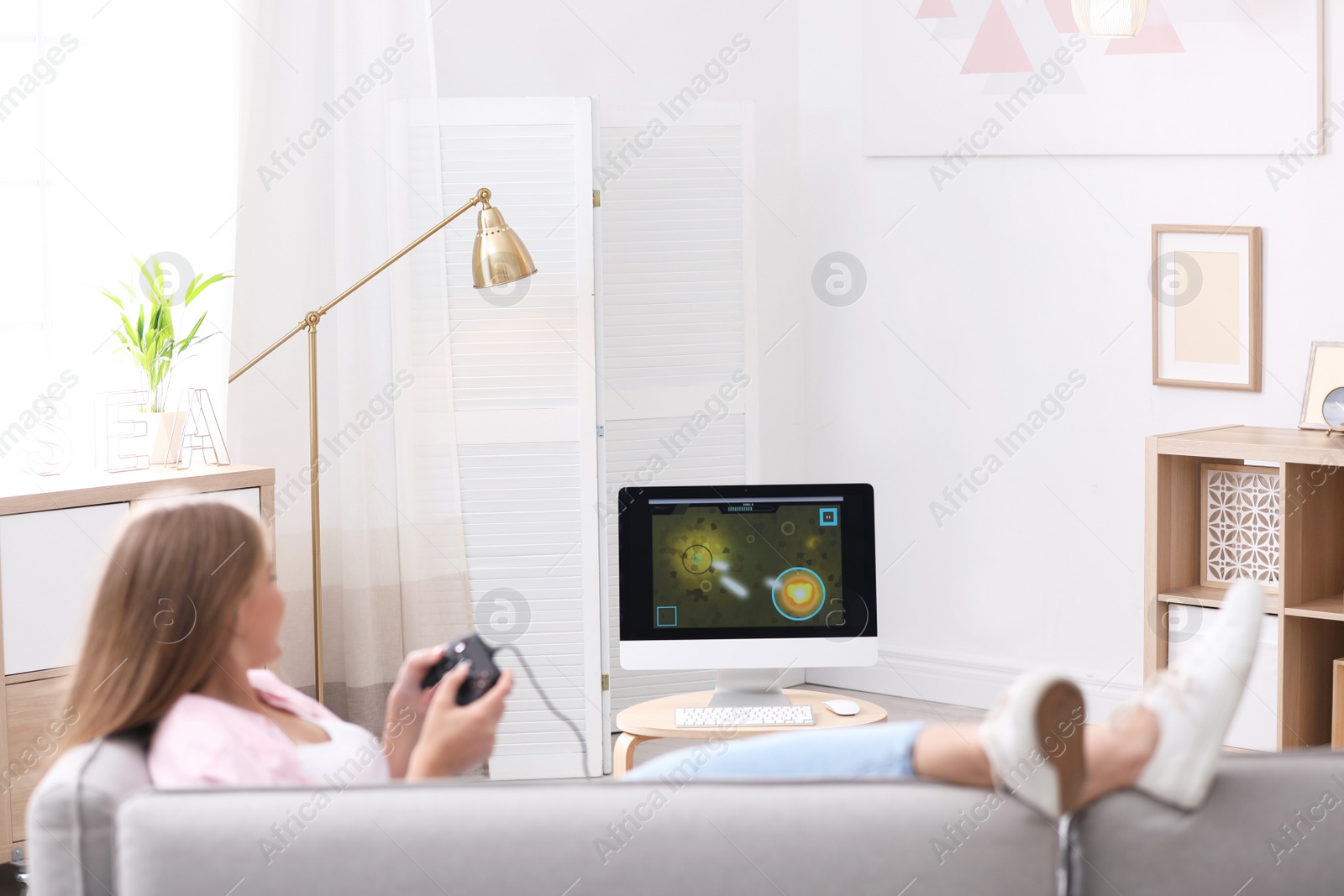 Photo of Emotional young woman playing video games at home