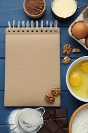 Blank recipe book and different ingredients on blue wooden table, flat lay. Space for text