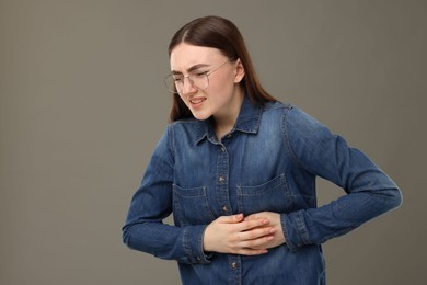 Photo of Woman suffering from stomach pain on grey background, space for text