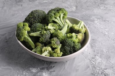 Photo of Bowl of fresh raw broccoli on grey textured table