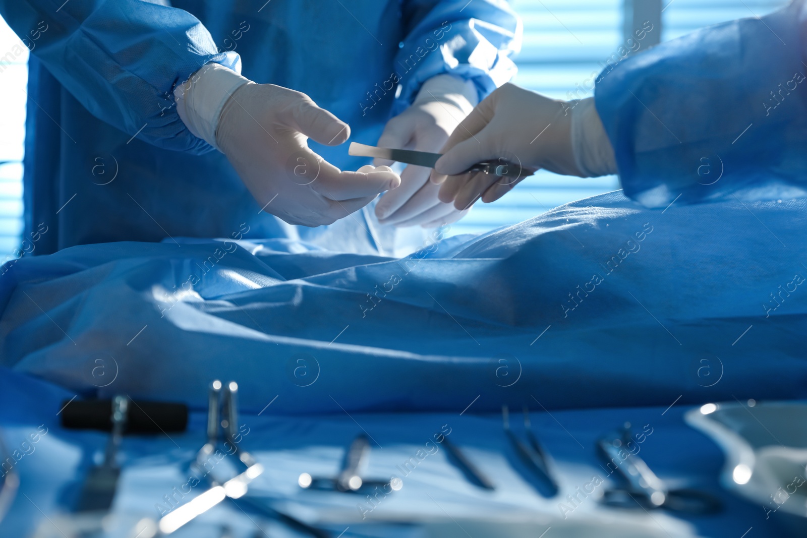 Photo of Professional surgeons with instruments performing operation in clinic, closeup