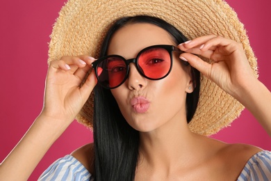 Beautiful woman wearing sunglasses on pink background, closeup