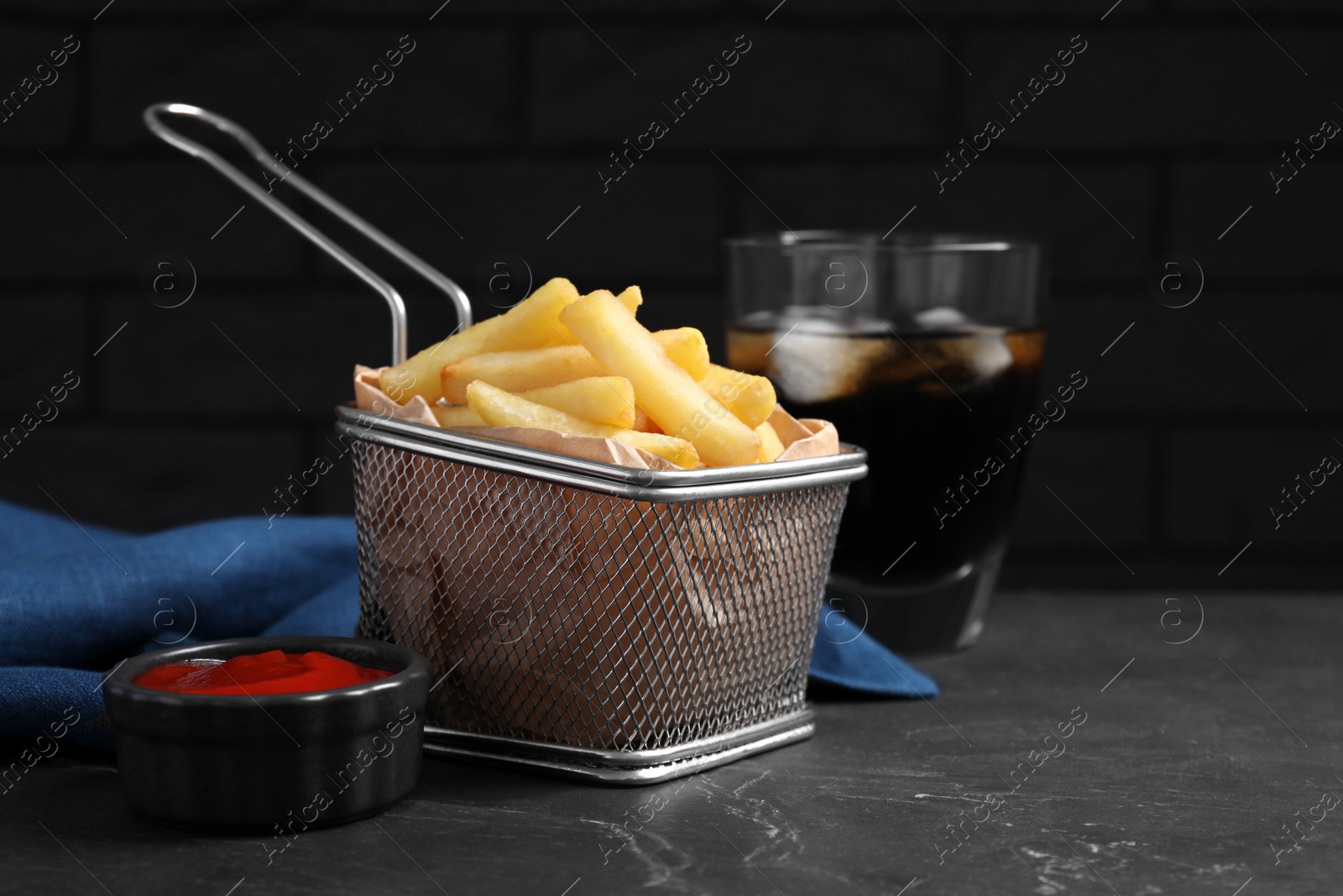 Photo of Tasty french fries, ketchup and soda drink on black table, closeup