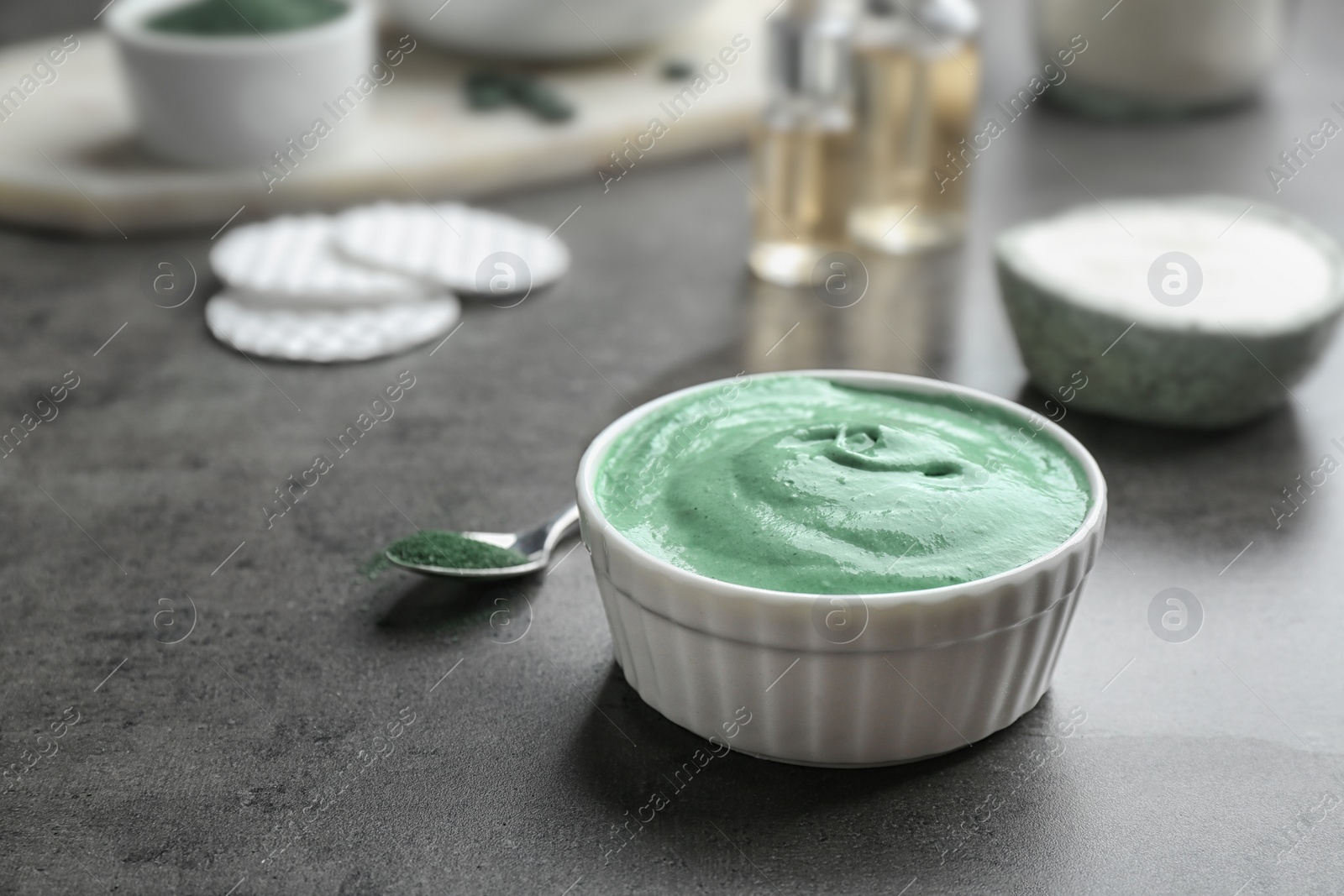 Photo of Bowl of spirulina facial mask on grey table