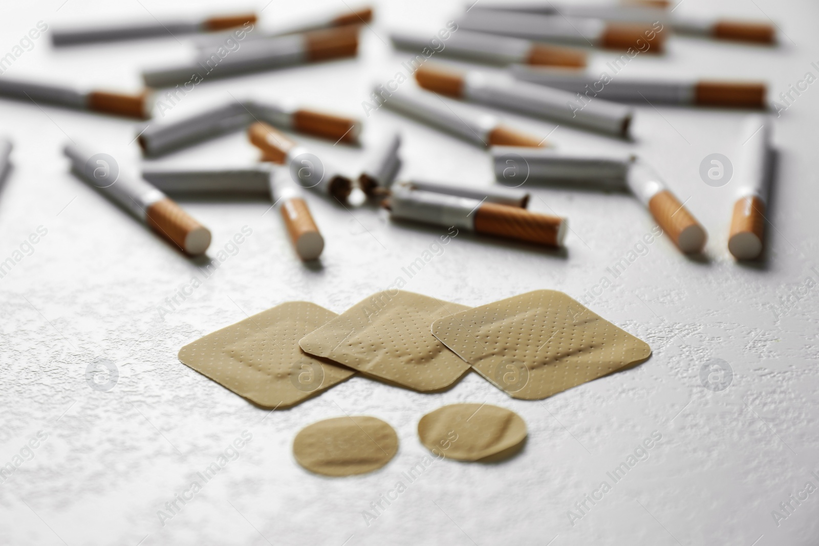 Photo of Nicotine patches and cigarettes on white table, closeup