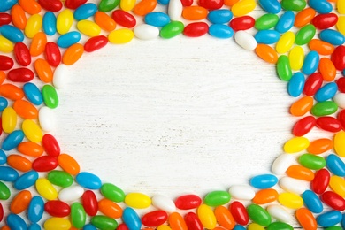 Photo of Frame of jelly beans on light background, top view. Space for text