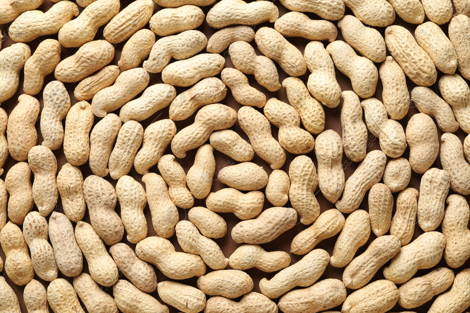 Photo of Many fresh unpeeled peanuts as background, top view