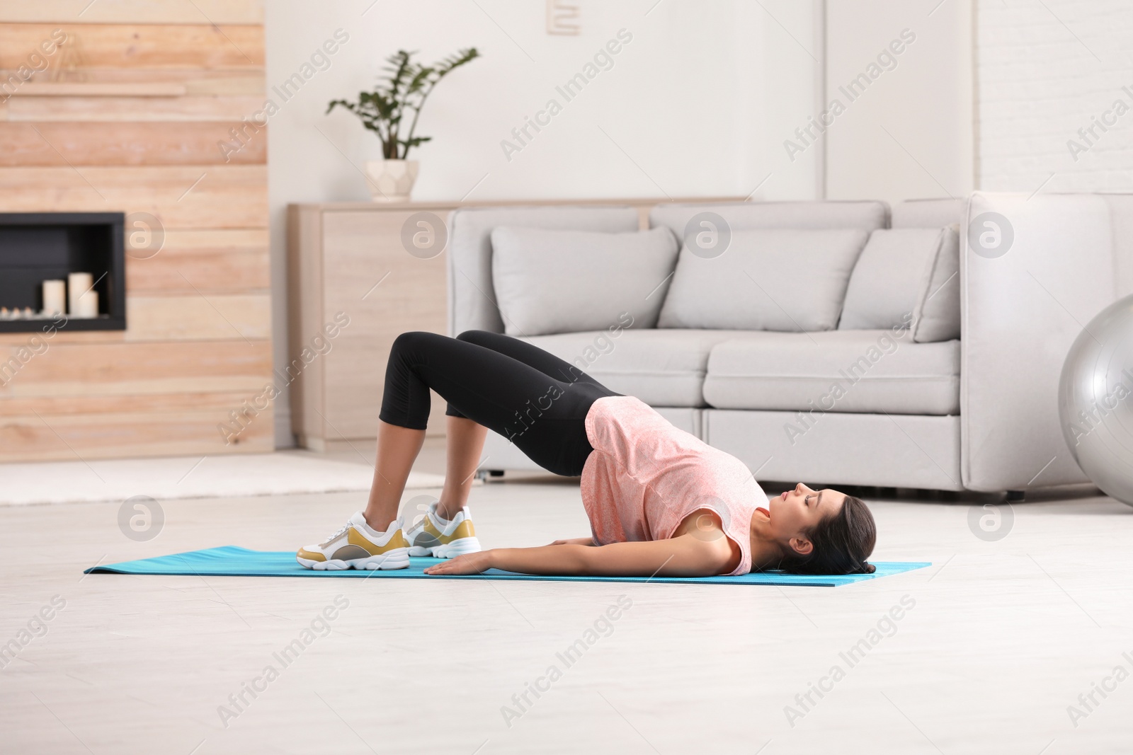 Photo of Young woman in fitness clothes doing exercise at home. Space for text