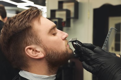 Professional hairdresser working with client in barbershop