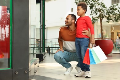 Family shopping. Happy father and son with colorful bags in mall