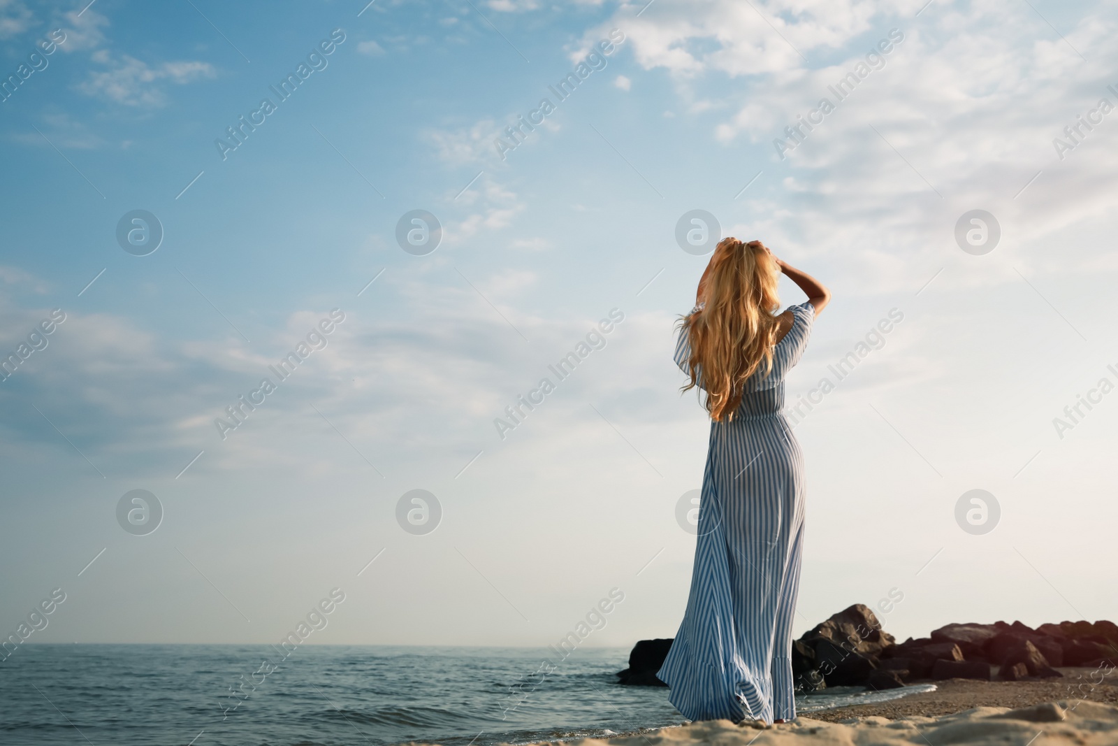 Photo of Young woman on sea beach, back view. Space for text