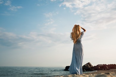 Young woman on sea beach, back view. Space for text