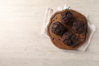 Delicious chocolate muffins on white wooden table, top view. Space for text