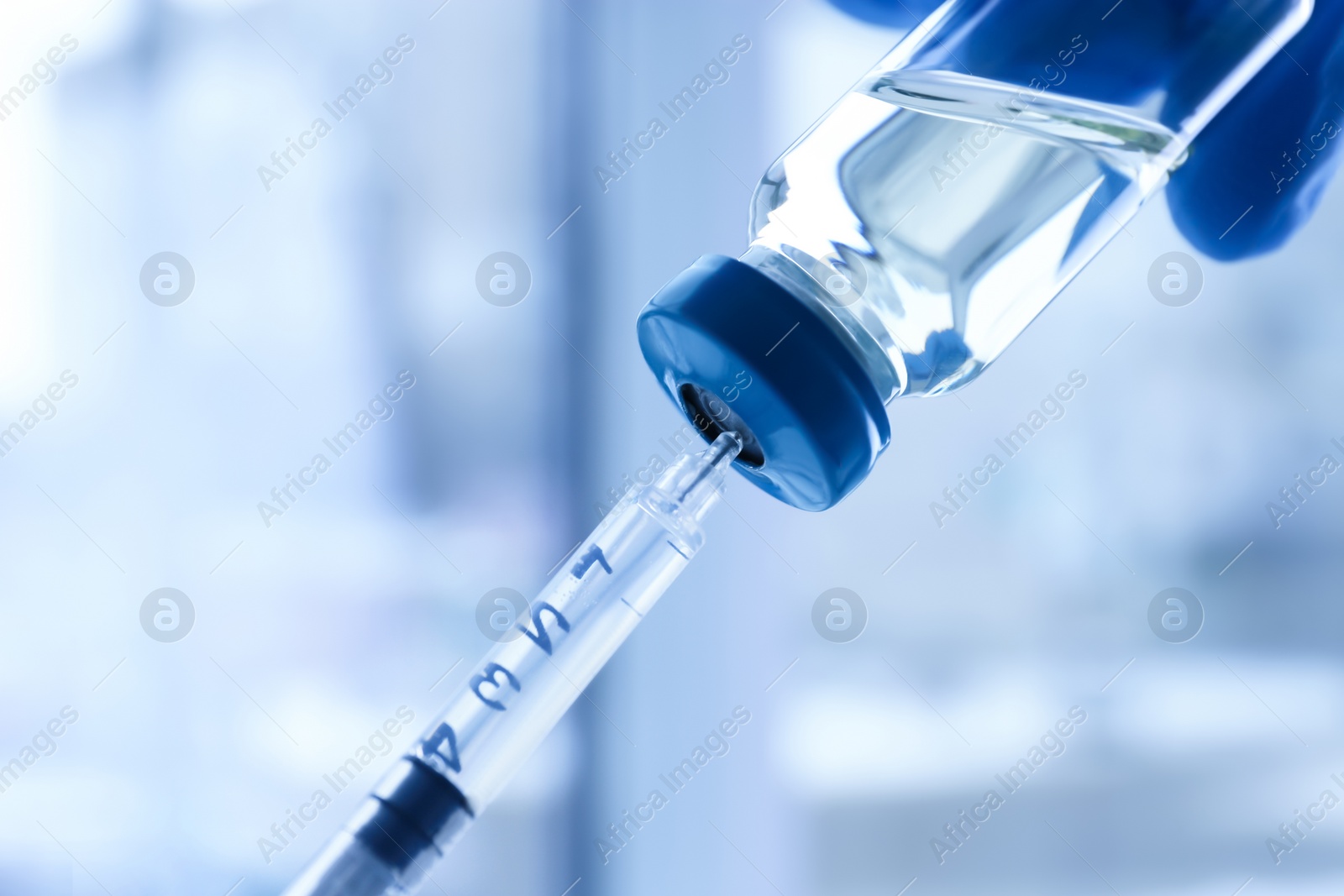 Photo of Doctor with syringe and medicine for vaccination on blurred background