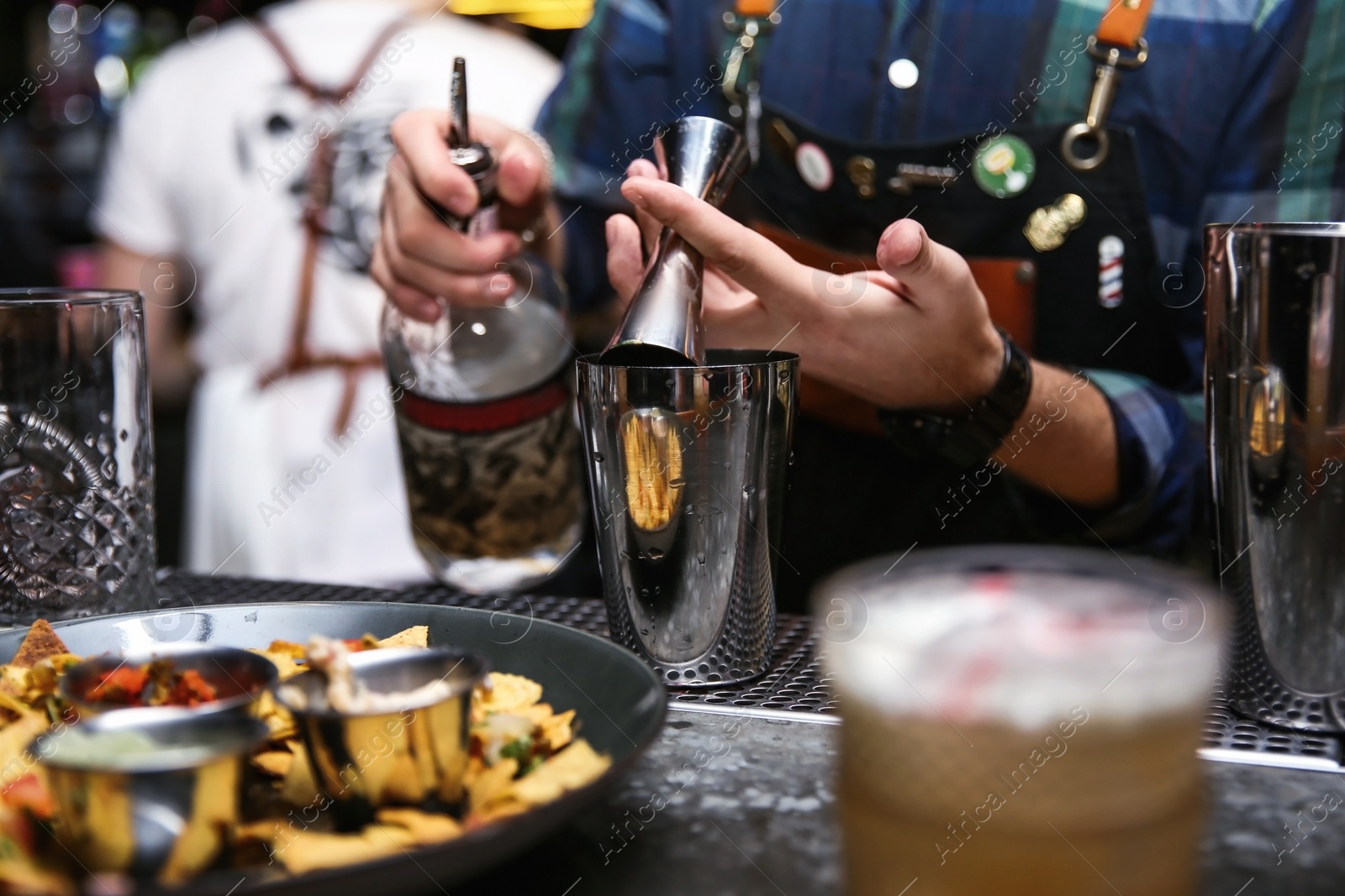 Photo of Bartender preparing tasty cocktail at counter in nightclub, closeup