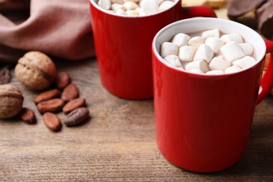 Composition of tasty cocoa with marshmallows in cups on wooden table