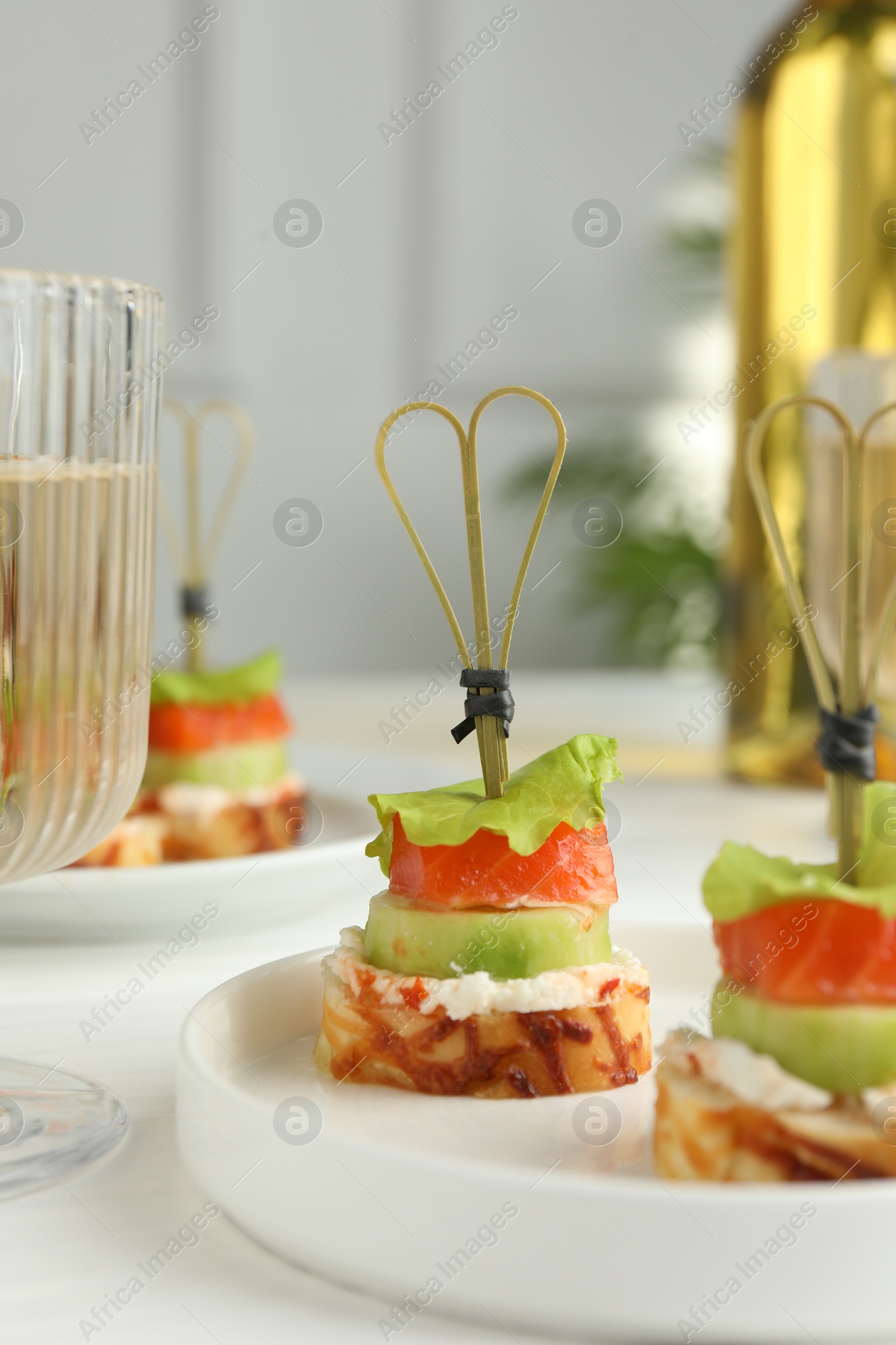 Photo of Tasty canapes with salmon, cucumber, bread and cream cheese on white table, closeup