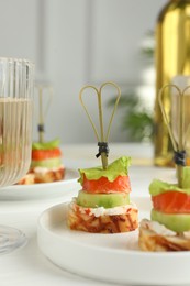 Photo of Tasty canapes with salmon, cucumber, bread and cream cheese on white table, closeup