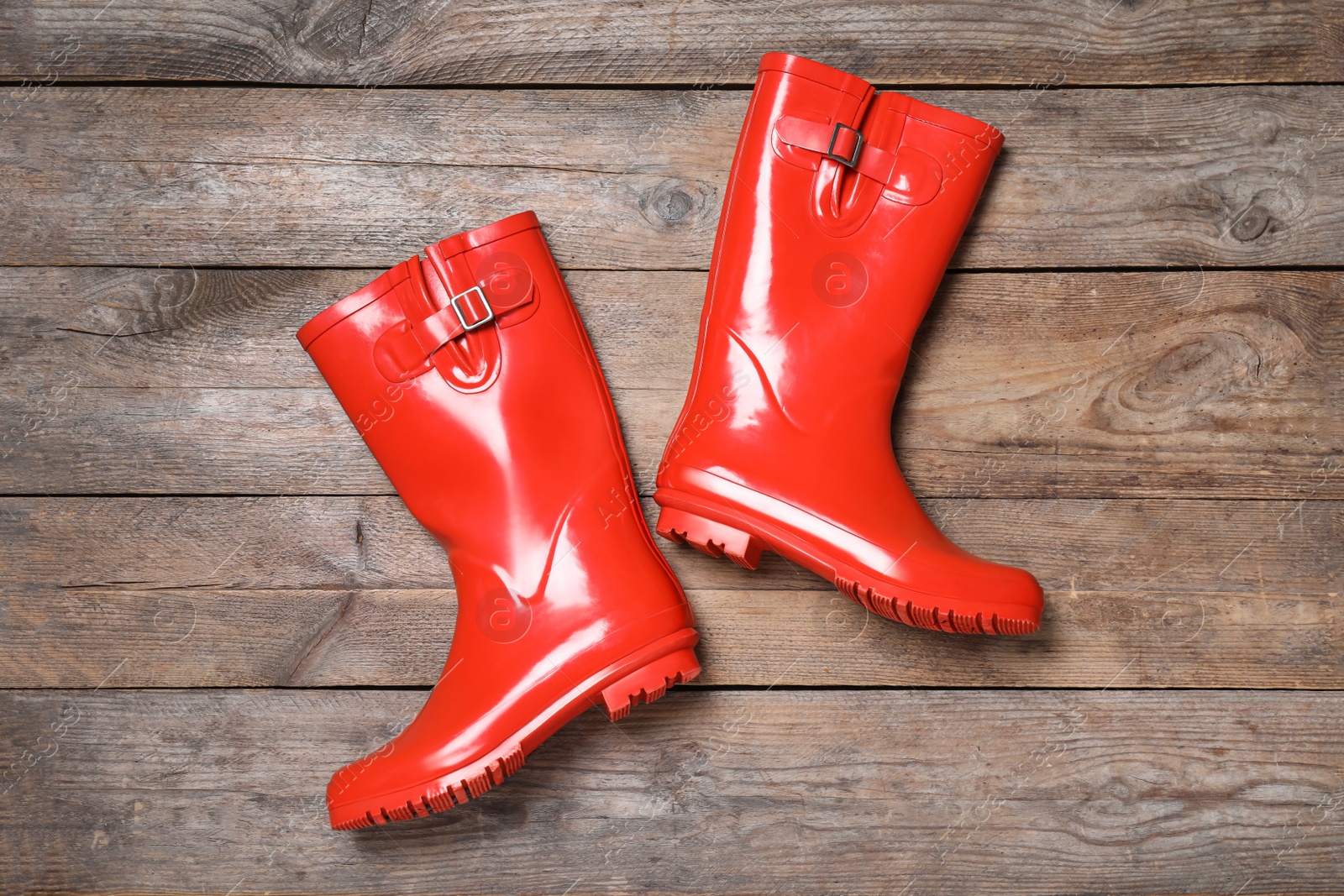 Photo of Pair of red rubber boots on wooden background, top view