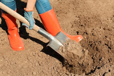 Photo of Woman digging soil with shovel outdoors. Gardening tool