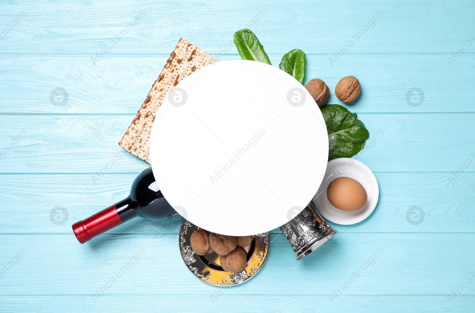 Photo of Frame made with symbolic Passover items and blank card on light blue wooden table, space for text. Pesah celebration