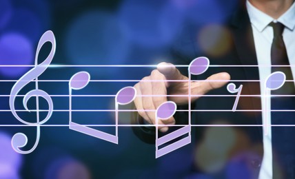 Musician pointing at staff with music notes and symbols on color background, closeup