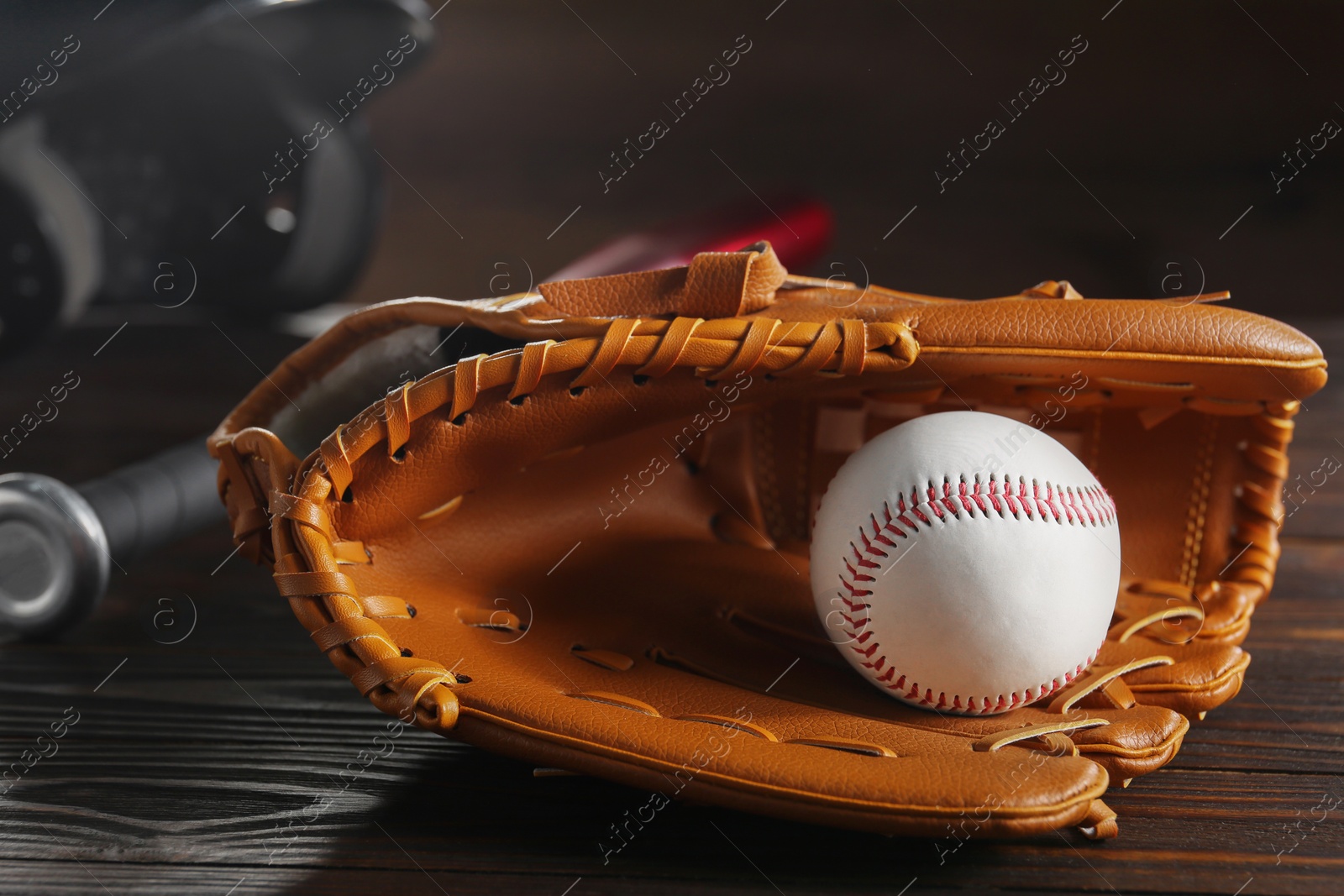 Photo of Baseball glove and ball on wooden table, closeup